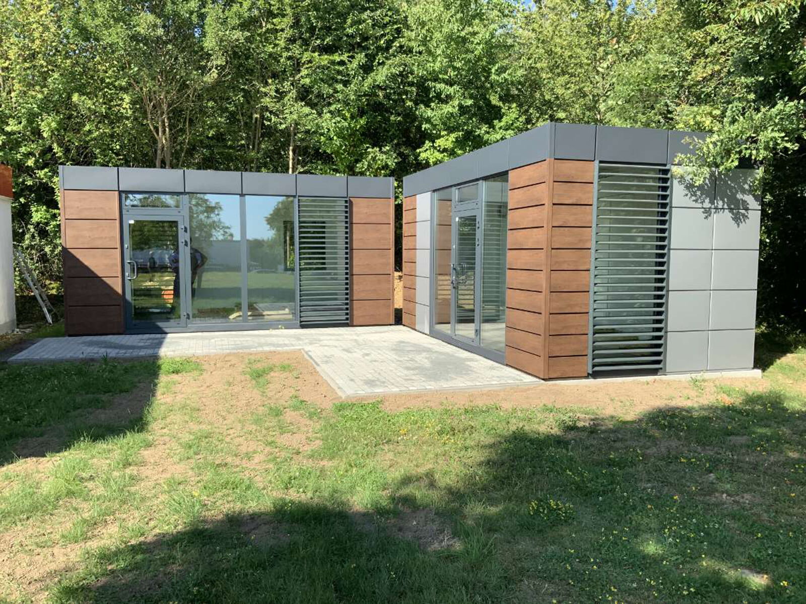 Deux conteneurs modulaires modernes avec façade en bois et métal dans la verdure      