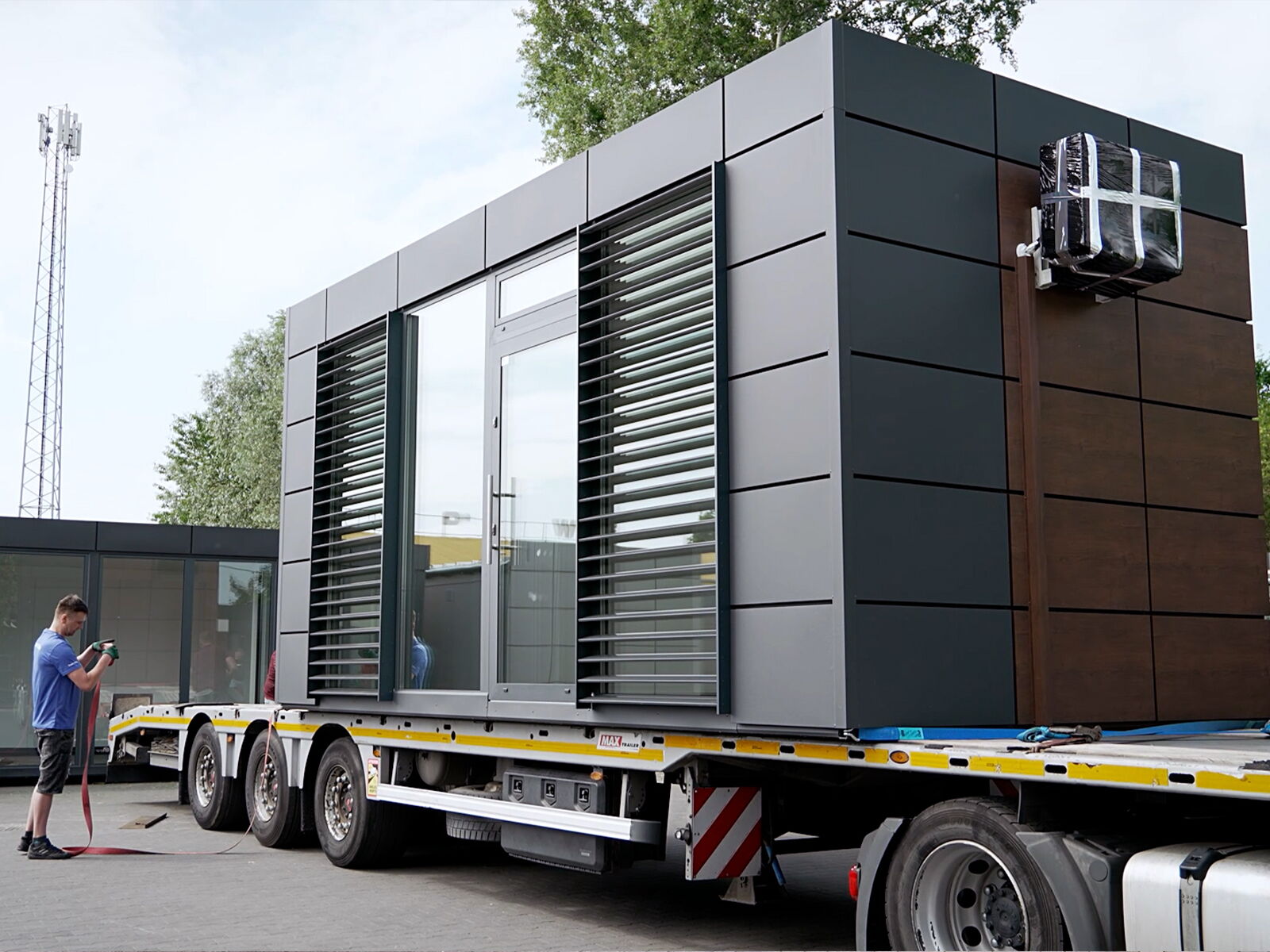 Transport d'un conteneur de bureau moderne avec façade métallique sur un camion      