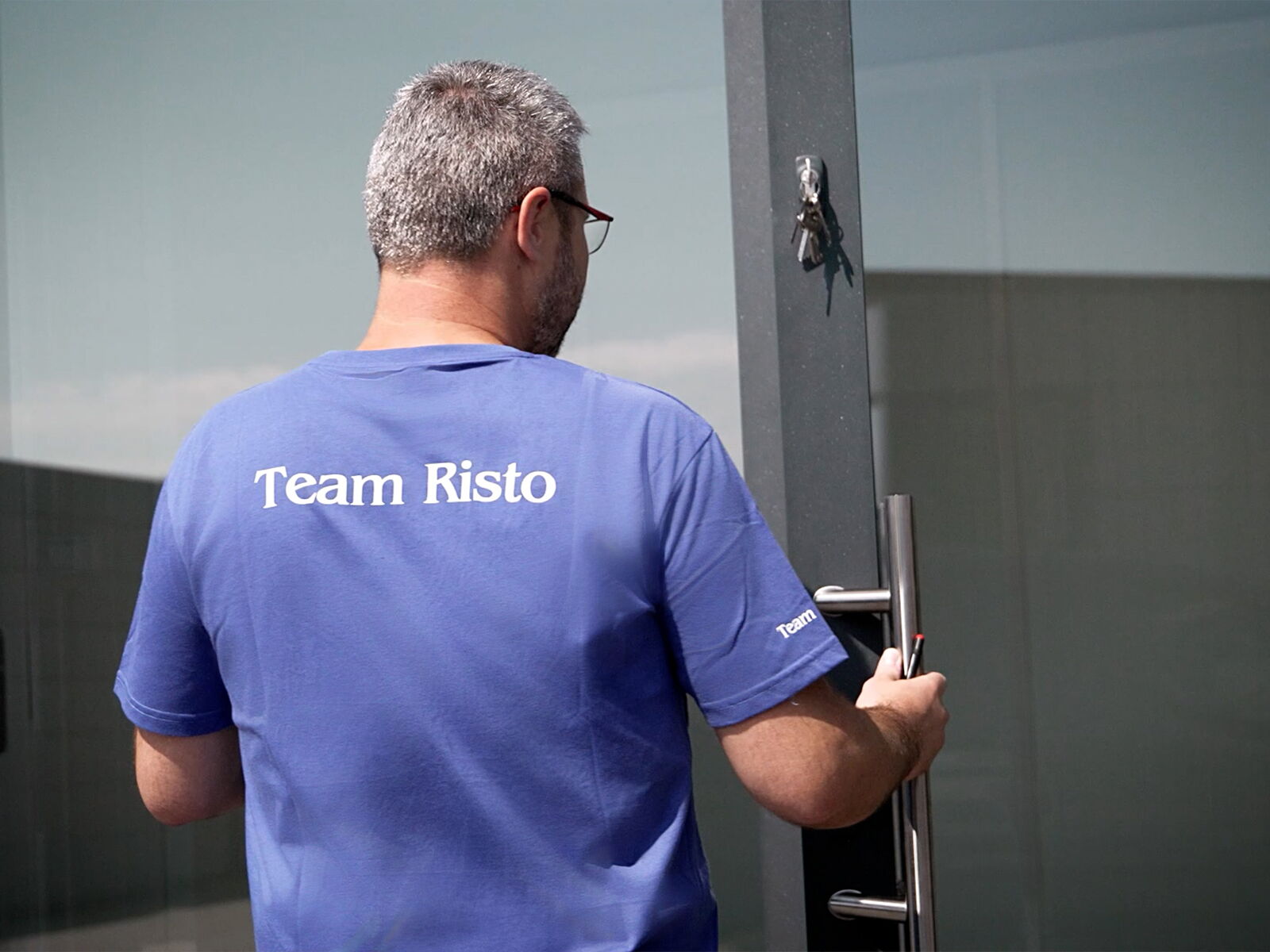 Employé de Risto ouvrant une porte vitrée, T-shirt avec impression Team Risto      
