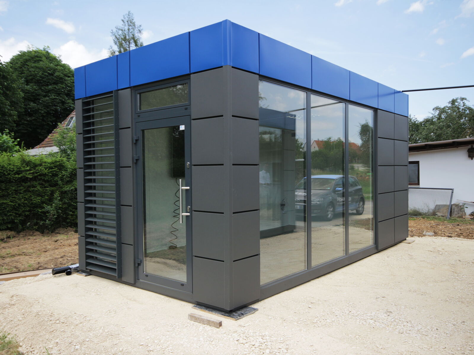 Conteneur de bureau moderne avec acrotère bleu et façade vitrée toute hauteur      